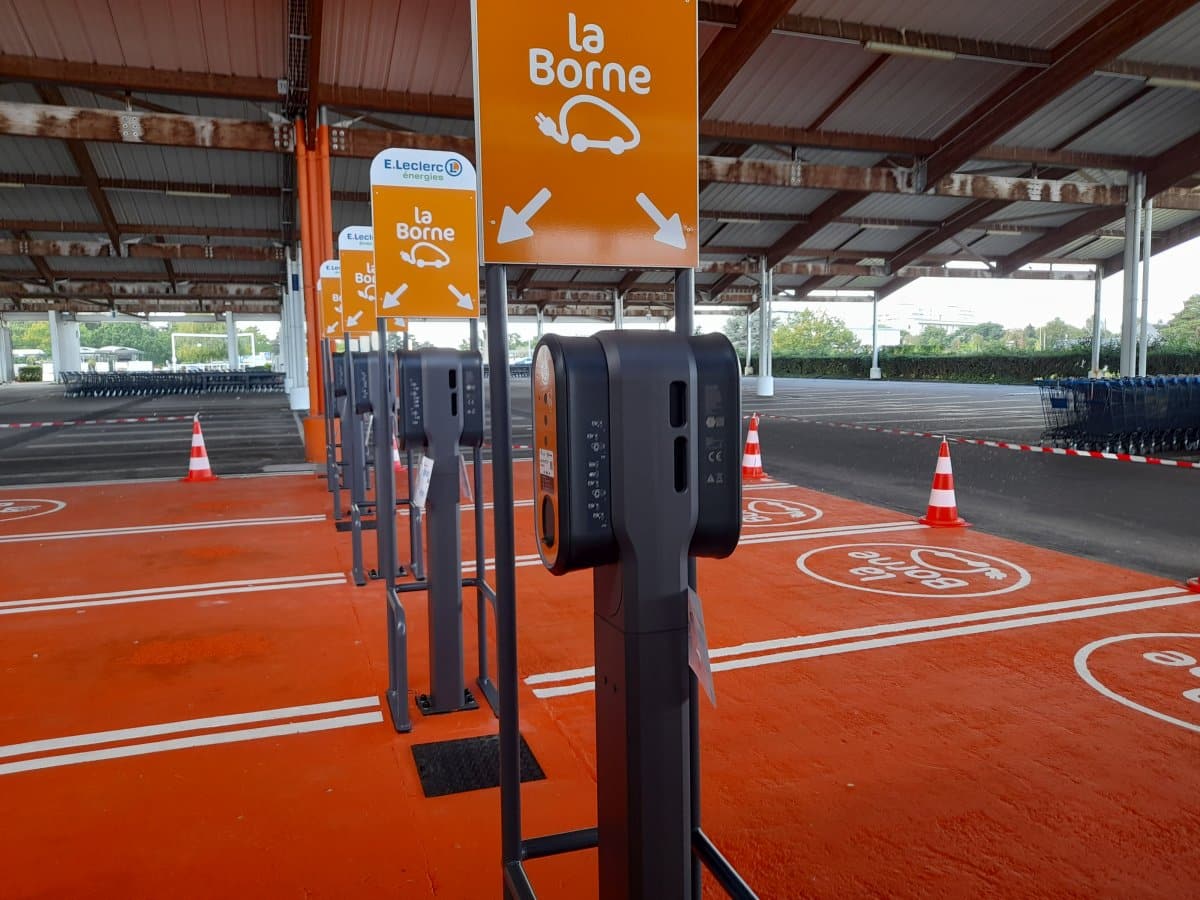 Borne de recharge pour véhicule électrique sur le parking d'un supermarché.